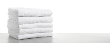 Gri masadaki katlanmış havlular beyaz arka plana karşı, yakın plan. Metin için boşluk