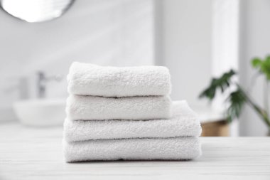 Katlanmış havlular banyodaki açık ahşap masada, yakın plan.