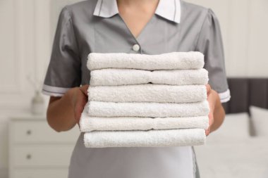 Otel odasında beyaz havlu yığını olan oda hizmetçisi, yakın plan.