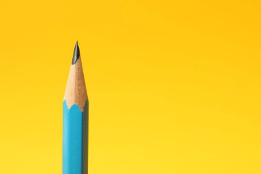 Sarı arka planda keskin bir grafit kalem, yakın plan. Metin için boşluk