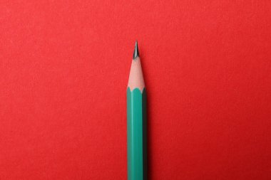 Kırmızı arkaplanda keskin bir grafit kalem, üst görünüm