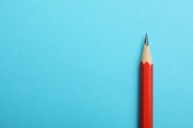 Açık mavi arka planda keskin bir grafit kalem, üst manzara. Metin için boşluk