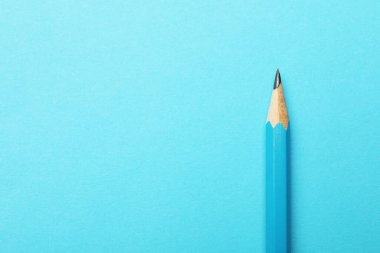 Açık mavi arka planda keskin bir grafit kalem, üst manzara. Metin için boşluk