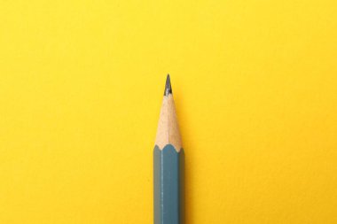 Sarı zemin üzerinde keskin bir grafit kalem, üst görünüm
