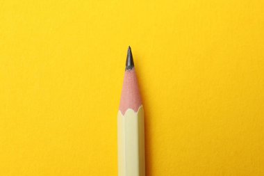 Sarı arkaplanda keskin bir grafit kalem, üst görünümde.