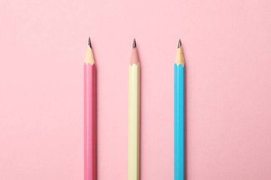 Pembe arka planda keskin grafit kalemler, üst görünüm