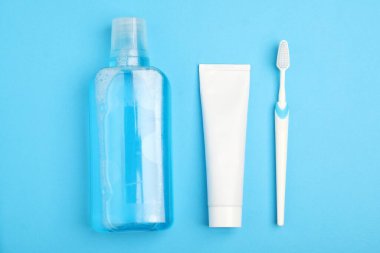 Açık mavi zemin üzerinde gargara, diş fırçası ve diş macunu.