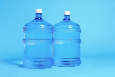 Açık mavi zemin üzerinde su olan soğutucu şişeler.