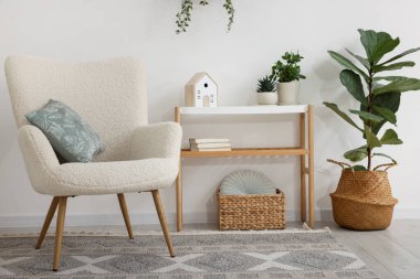 Şık bir koltuk, konsol masası ve oda çiçekleri. İç tasarım