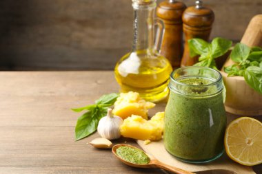Kavanozda taze pesto sosu ve ahşap masada malzemeler, yakın plan. Metin için boşluk