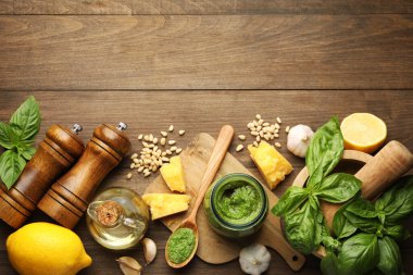 Kavanozda taze pesto sosu ve ahşap masada malzemeler. Metin için boşluk