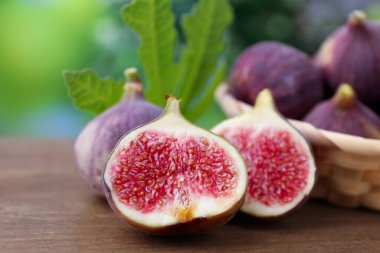 Taze incir ve yeşil yaprak dışarıda, ahşap masada, yakın plan.