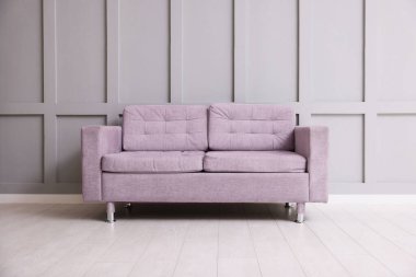 Gri duvarın yanındaki rahat menekşe kanepe