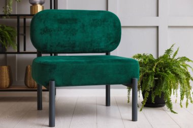 Gri duvarın yanında farklı dekorları olan şık bir koltuk ve askı. İç tasarım