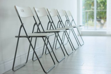 Beyaz duvarın yanında bir sürü şık sandalye.