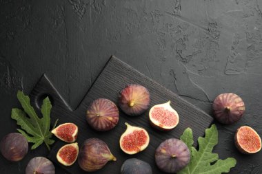 Taze incir ve yeşil yapraklar siyah desenli masada, düz yerde. Metin için boşluk