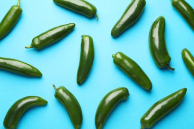 Açık mavi arka planda yeşil biberler, düz uzanmış