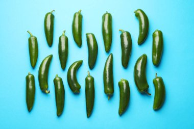 Açık mavi arka planda yeşil biberler, düz uzanmış