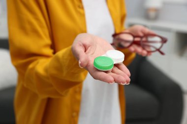 Gözlükler ve kontakt lensler arasında seçim yapan kadın, yakın plan.