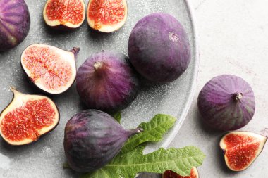 Taze incir ve yeşil yaprak. Gri masa, üst manzara.