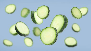 Taze salatalık parçaları grimsi mavi arka plana düşüyor.