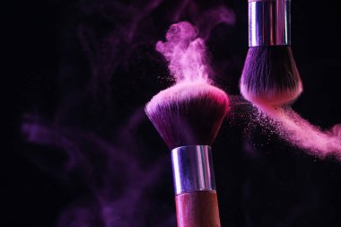 Renkli göz gölgeli makyaj fırçaları siyah arka planda neon ışıkları, yakın plan. Metin için boşluk