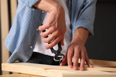 Kapalı alanda kıskacı olan tahta çiviyi söken adam, yakın plan.