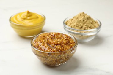 Beyaz mermer masa üzerinde farklı hardal türleri, yakın plan.