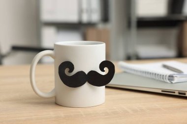 Babalar Günün kutlu olsun. Kağıt bıyıklı fincan ve ahşap masa üzerinde kitaplar, yakın plan.