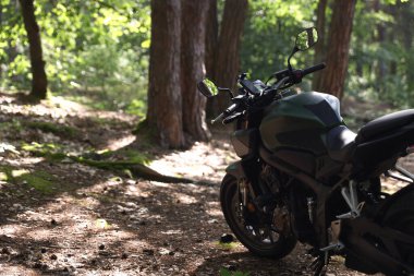 Ormana park edilmiş modern siyah motosiklet. Metin için boşluk