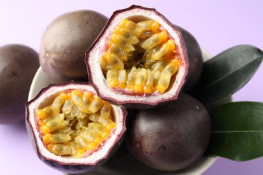 Mor arka planda yeşil yapraklı taze tutku meyveleri, yakın plan.