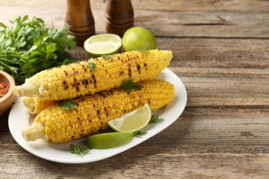 Maydanozlu mısır koçanları ve ahşap masada limon dilimleri. Metin için boşluk