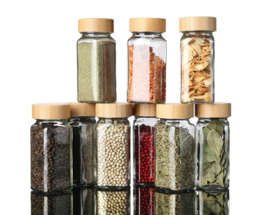 Ayna yüzeyindeki kavanozlarda beyaz arka plana karşı çok farklı aromatik baharatlar var.