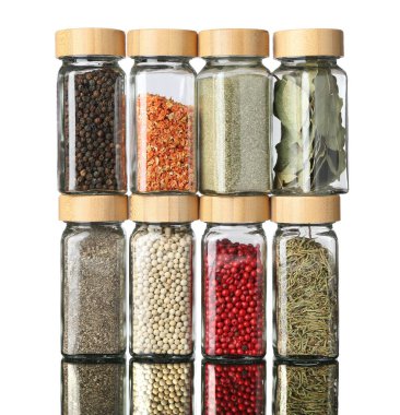 Ayna yüzeyindeki kavanozlarda beyaz arka plana karşı çok farklı aromatik baharatlar var.