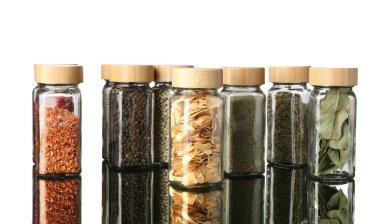 Ayna yüzeyindeki kavanozlarda beyaz arka plana karşı çok farklı aromatik baharatlar var.