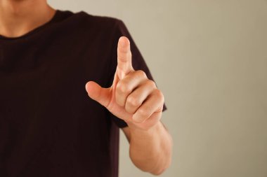 Adam açık gri arkaplanda bir şeye dokunuyor, yakın plan. Metin için boşluk