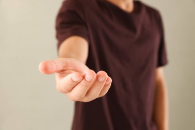 Açık gri arka planda bir şey tutan adam, yakın plan.