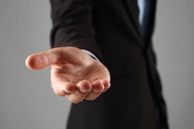 Gri arkaplanda bir şey tutan adam, yakın plan.