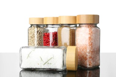 Ayna yüzeyindeki kavanozlardaki farklı baharatlar beyaz arkaplana karşı