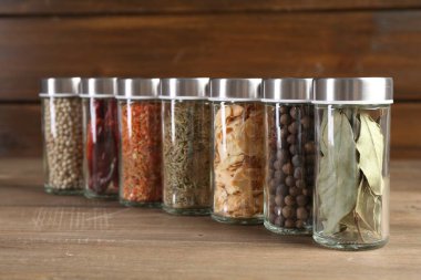 Ahşap masada farklı baharatlar ve kavanozlar.