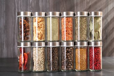 Gri ahşap masada cam kavanozlarda farklı baharatlar