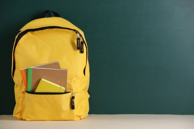 Tahtanın yanındaki masada defterli sarı sırt çantası. Metin için boşluk