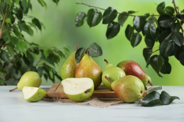 Beyaz mermer masada taze armutlar ve açık havada yeşil yapraklar.