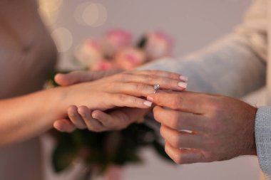 Evlilik teklifi yapıyor. Adamın biri kız arkadaşının parmağına nişan yüzüğü takıyor. Geçmişi bulanık, yakın plan. Bokeh etkisi