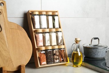 Cam kavanozlarda farklı baharatlar ve mutfakta açık gri masada yağlar.