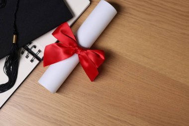 Mezuniyet şapkası, diploma ve defter tahtada, düz yerde. Metin için boşluk