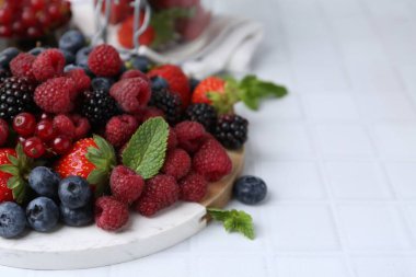 Farklı olgun böğürtlen ve nane yaprakları beyaz fayanslı masada, yakın plan. Metin için boşluk