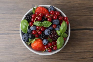 Farklı olgun böğürtlen ve fesleğen yaprakları ahşap masada, üst manzara