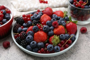 Açık gri dokulu masada farklı olgun meyveler, yakın plan.