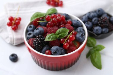 Farklı olgun böğürtlen ve fesleğen yaprakları beyaz fayanslı masada, yakın plan